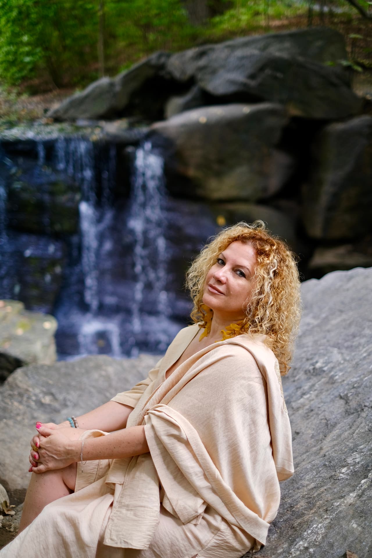 Irina Devi sitting beside a waterfall